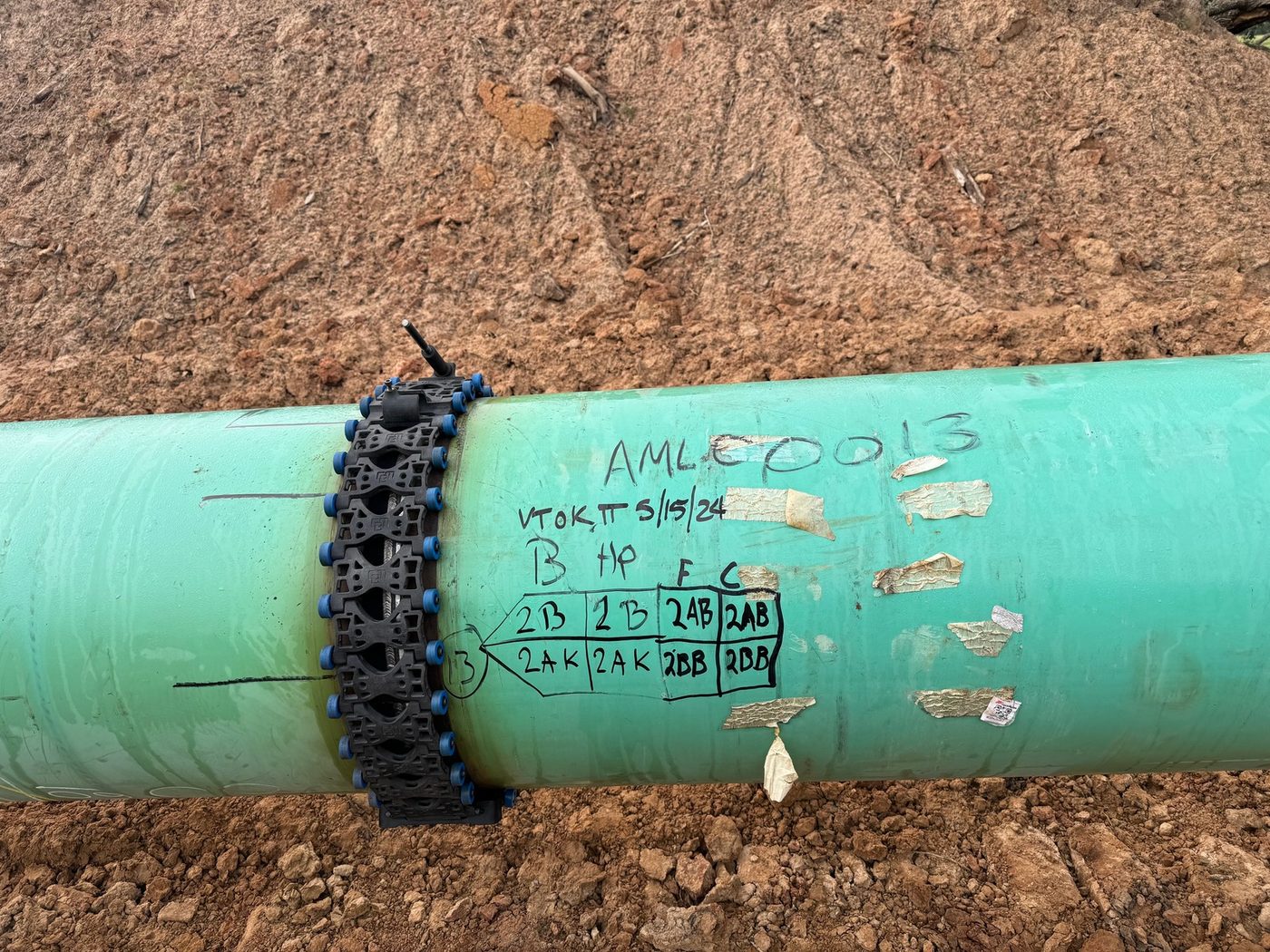 Automated ultrasonic testing scanner band clamped on a coated pipeline weld in the field