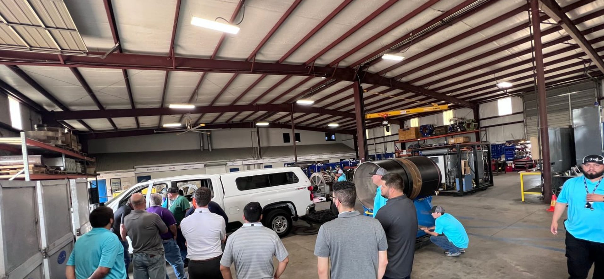 RAE Energy team touring the fabrication shop, with an automated scanning truck and coated pipe spool